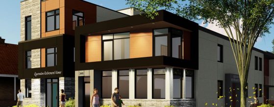 Modern two-story building with large windows and people walking on the sidewalk, surrounded by landscaping and trees under a clear sky.