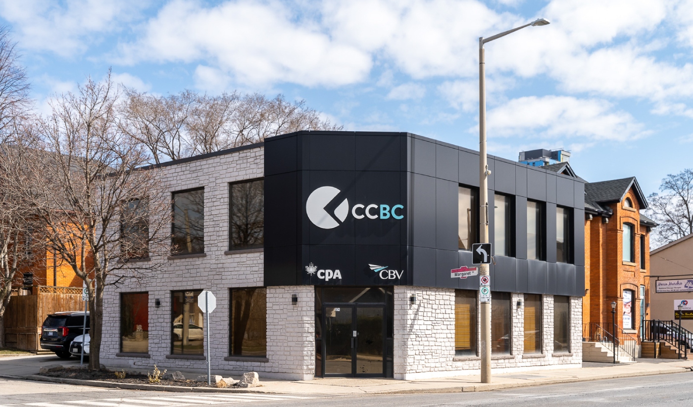 Two-story corner office building at 374 Main Street West with CCBC, CPA, and CBV logos on the facade. The building features white brick and black paneling, large windows, and a street sign in front.
