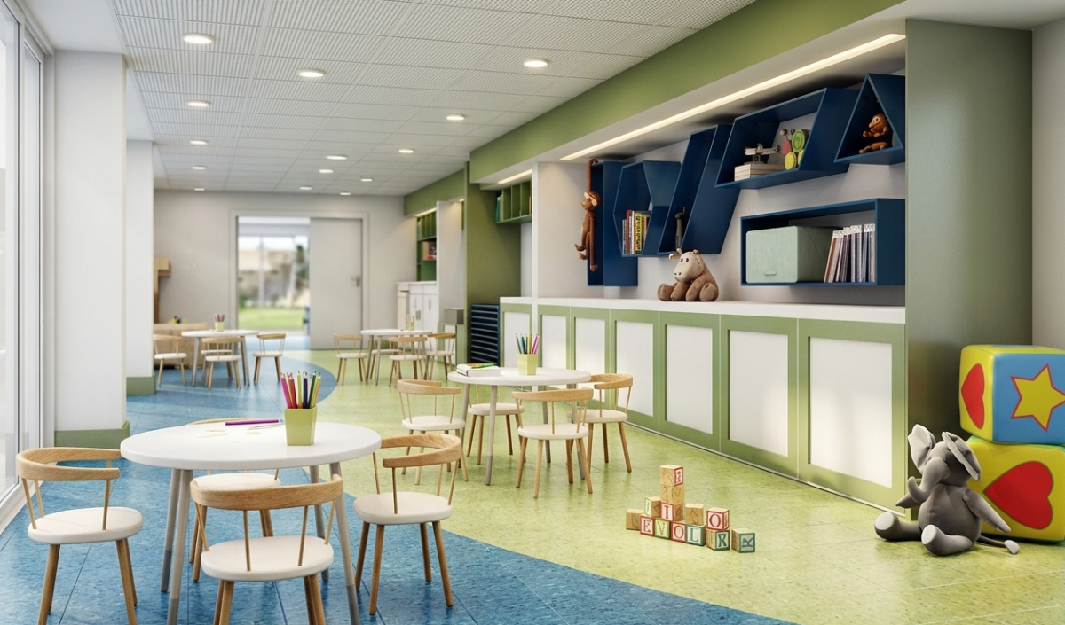 A brightly lit children’s classroom with small tables and chairs, toys, colored pencils, stuffed animals, and bookshelves against the wall.