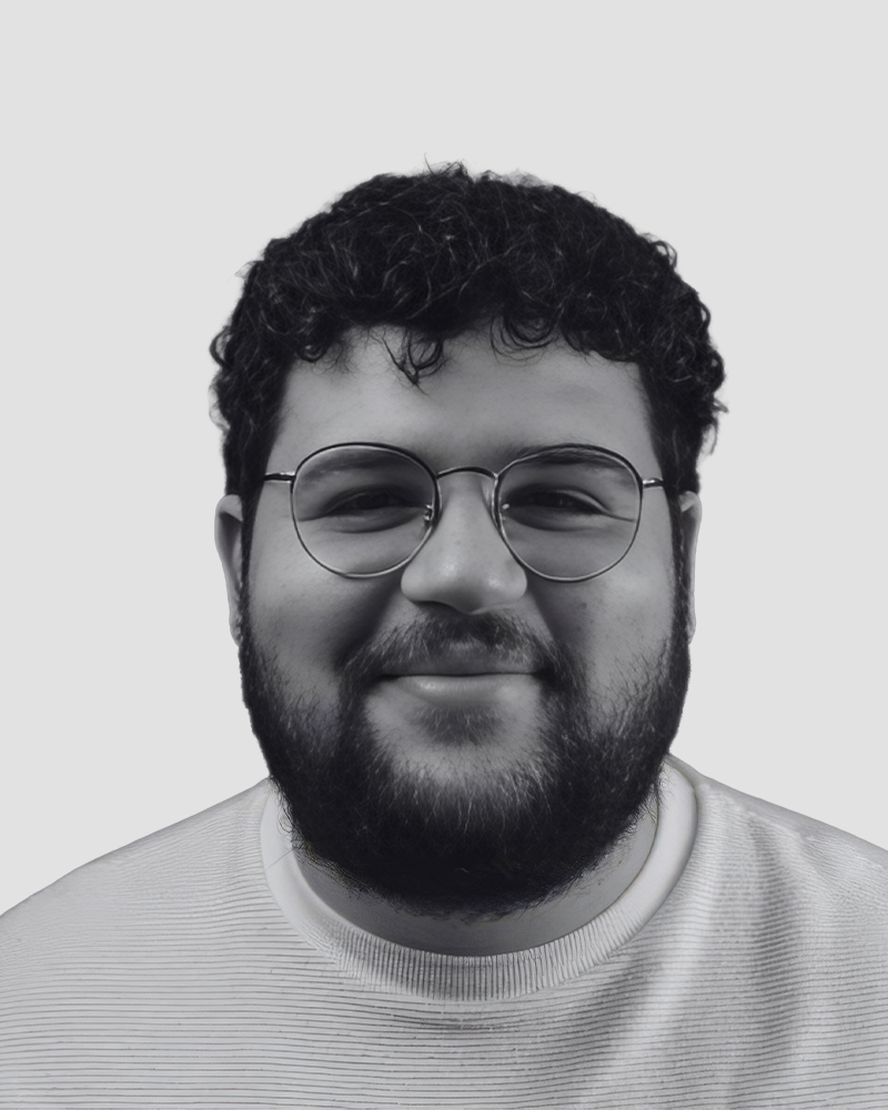 A headshot of a smiling man with a beard and round glasses.