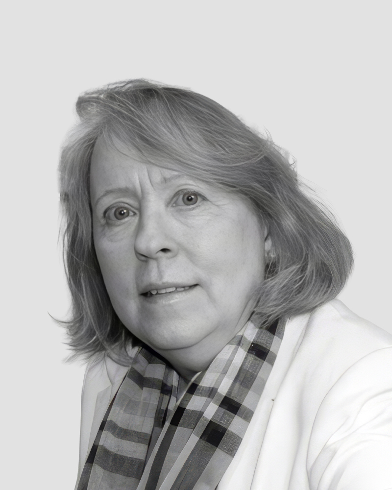 Head-and-shoulders portrait of a middle-aged woman wearing a blazer and a plaid scarf.